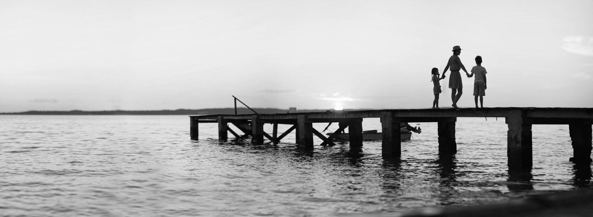 A black and white photo of two people standing on a dock